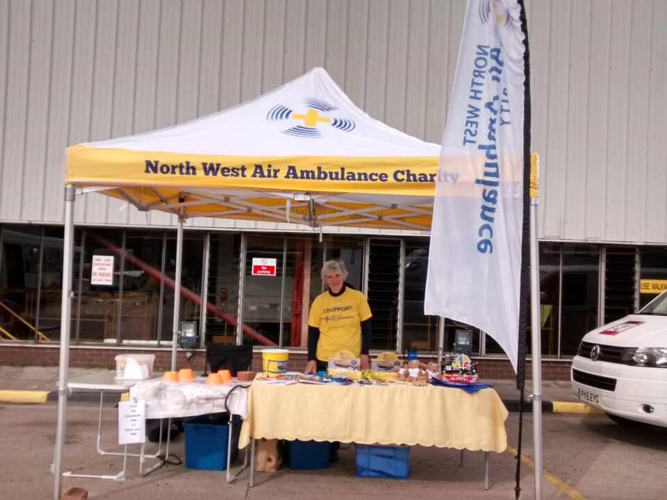 Volunteer Sarah, stood under a North West Air Ambulance Charity gazebo at an event 