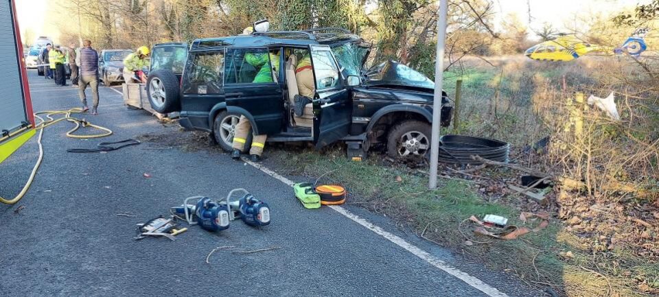 Car crashed into tree with medical crew on scene and helicopter in background 