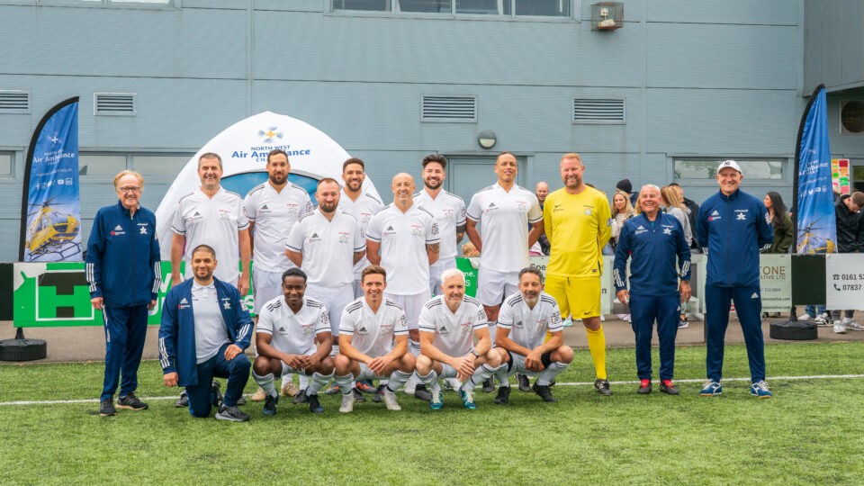 a group of people stood in front of an nwaa gazebo who are dressed in football kits 