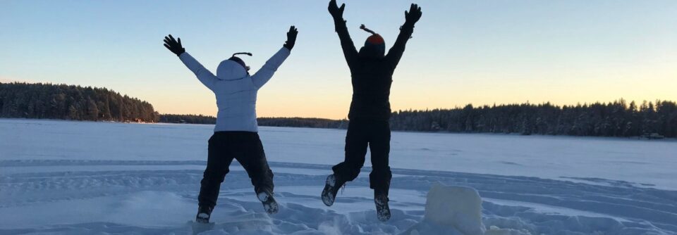 Two people doing a star jump pose in the snow