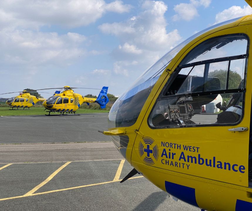 Three yellow charity helicopters sat on a helipad